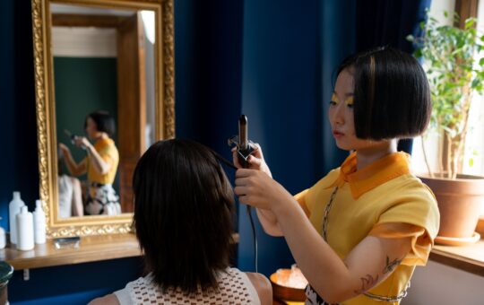 Hairstylist carrying out detailed hair styling work on a client in a professional salon