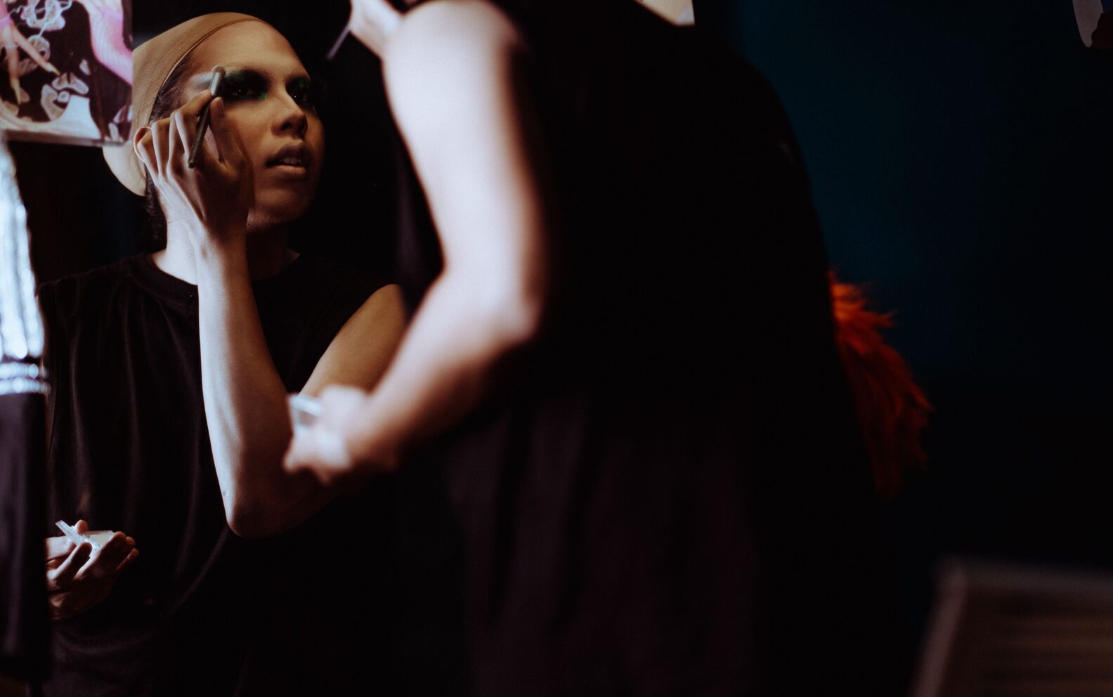 Theatre performer applying stage makeup at a dressing room mirror